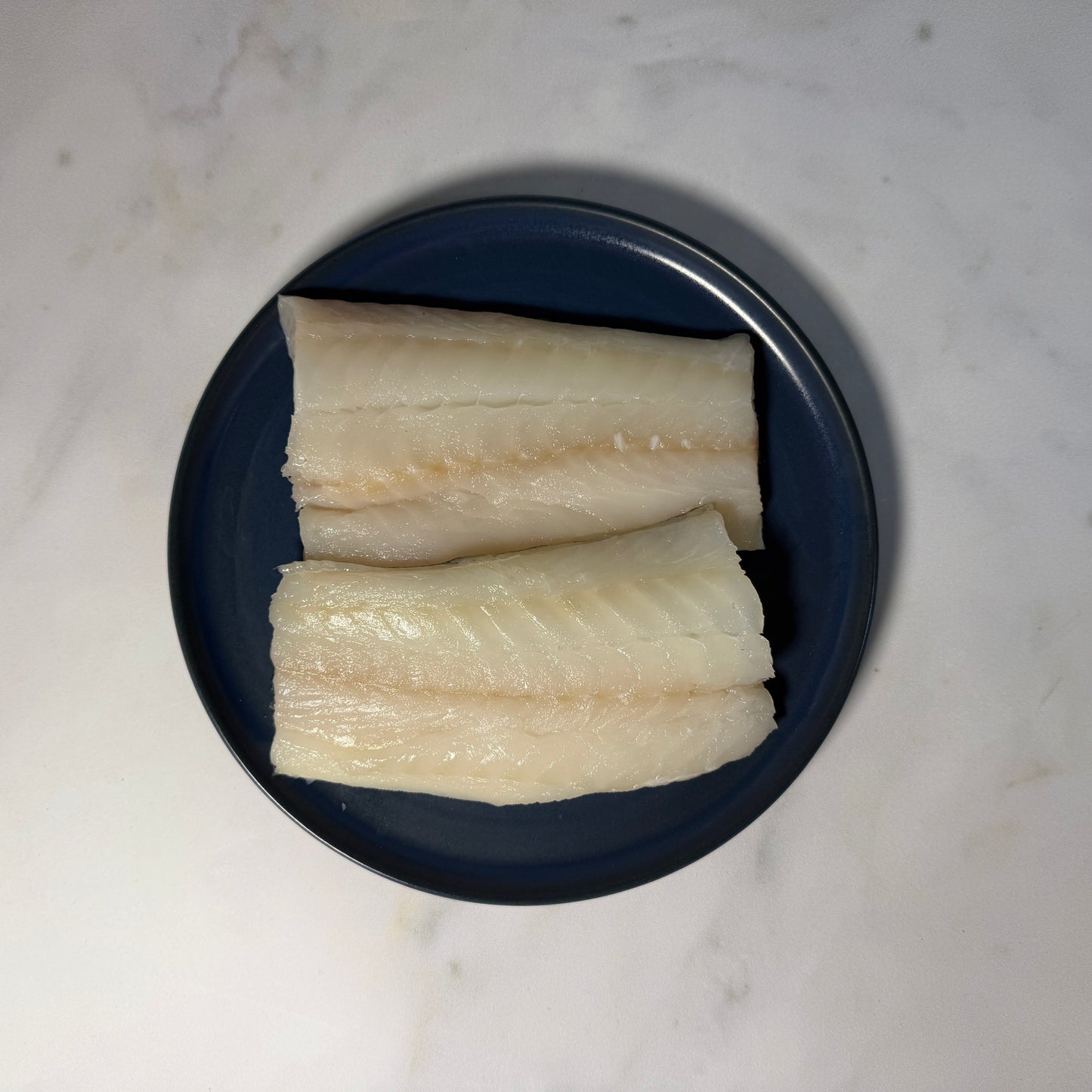 Fresh Wild Cod Fillets on a slate background, from Hamiltons Fish