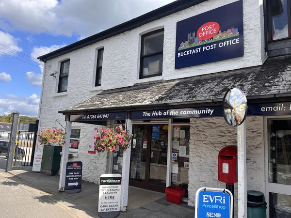 Buckfast Post Office building with a sign on a clear day